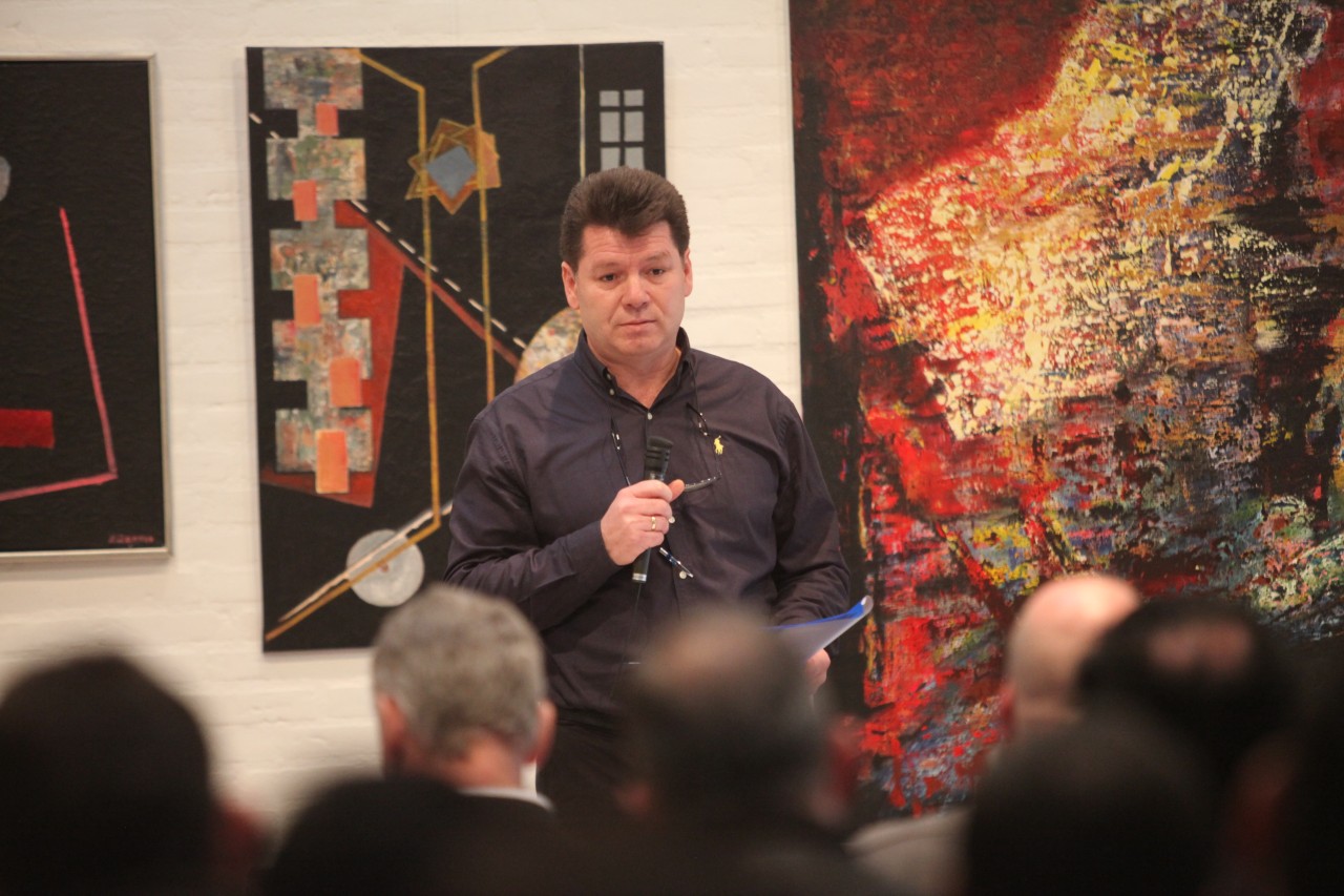 Man in black shirt standing in front of seated crowd