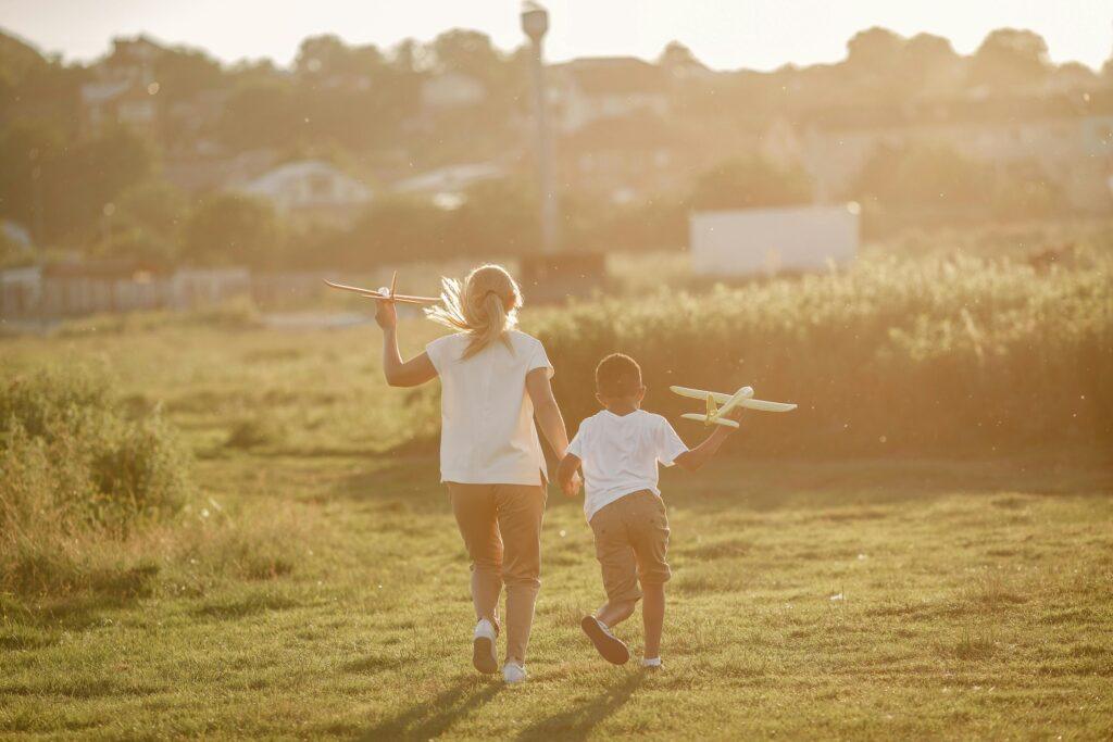 A Boy and Girl Running with Toy Planes