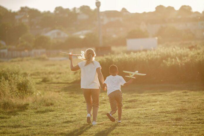 A Boy and Girl Running with Toy Planes