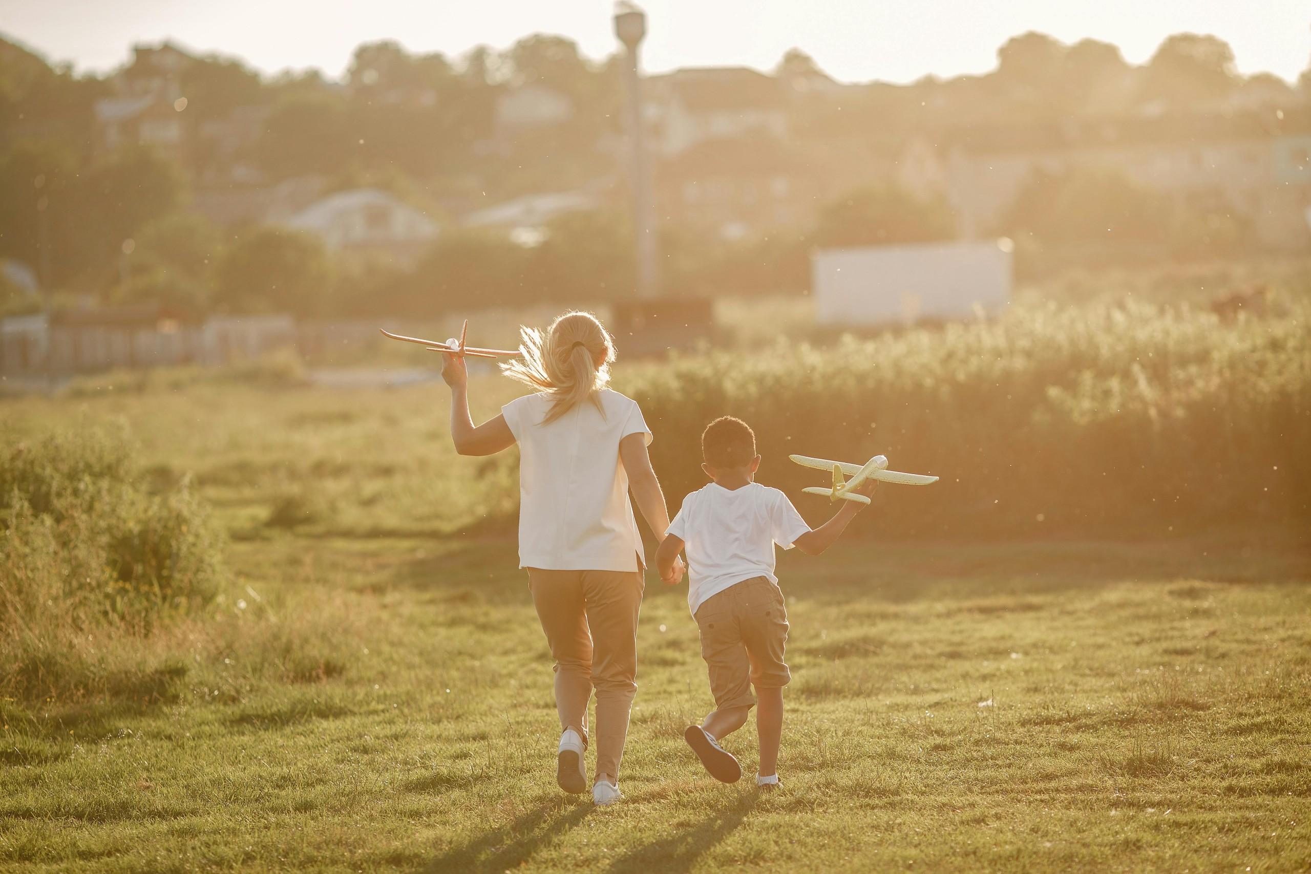 A Boy and Girl Running with Toy Planes