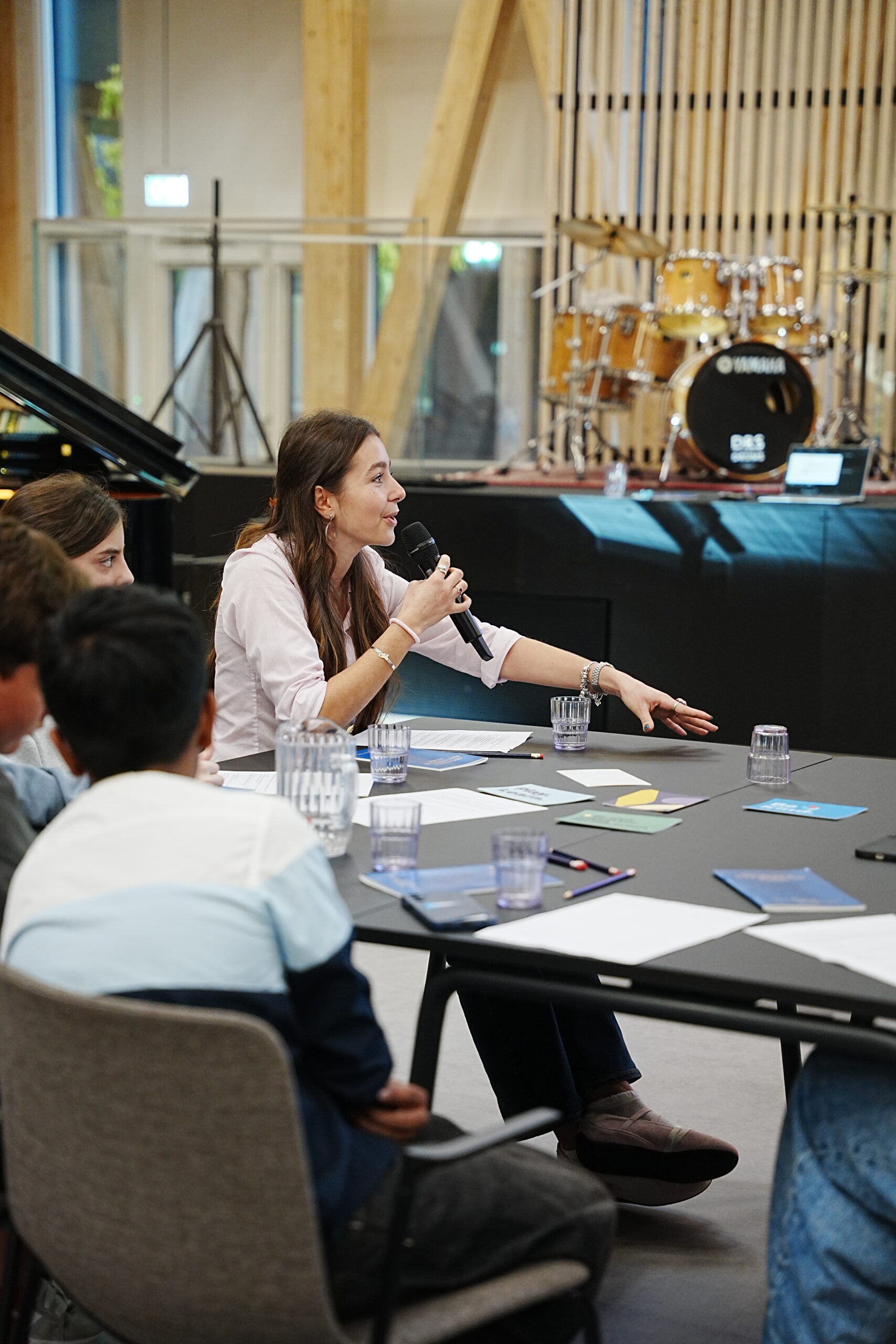 Woman speaking on a microphone with students