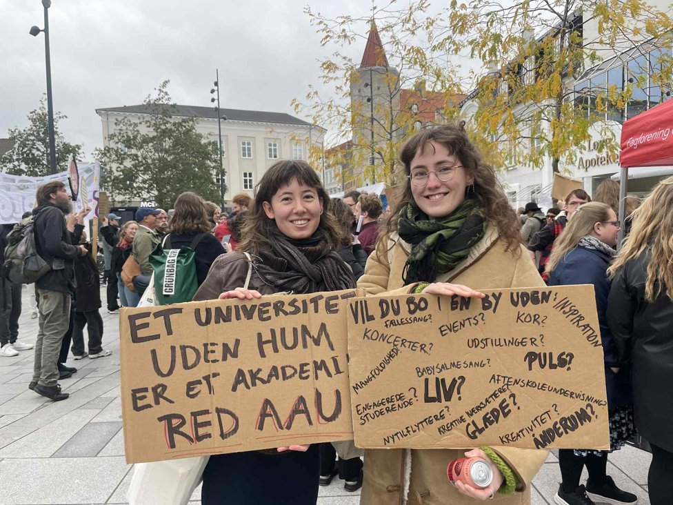 Two women students holding cardboards with writings in black
