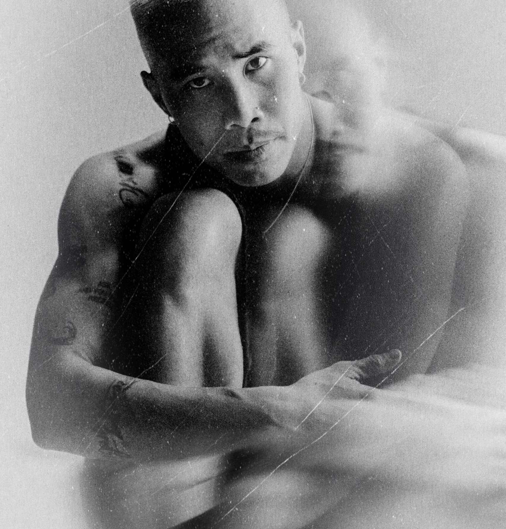 Black and white picture of a man sitting in foetal position looking sad