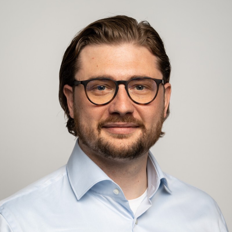 Passport size image of a man in glasses and white shirt