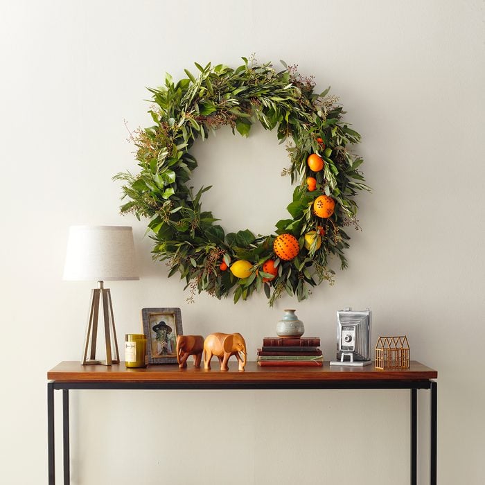 Wall decorated with a Christmas wreath with a table in front with stuff on it