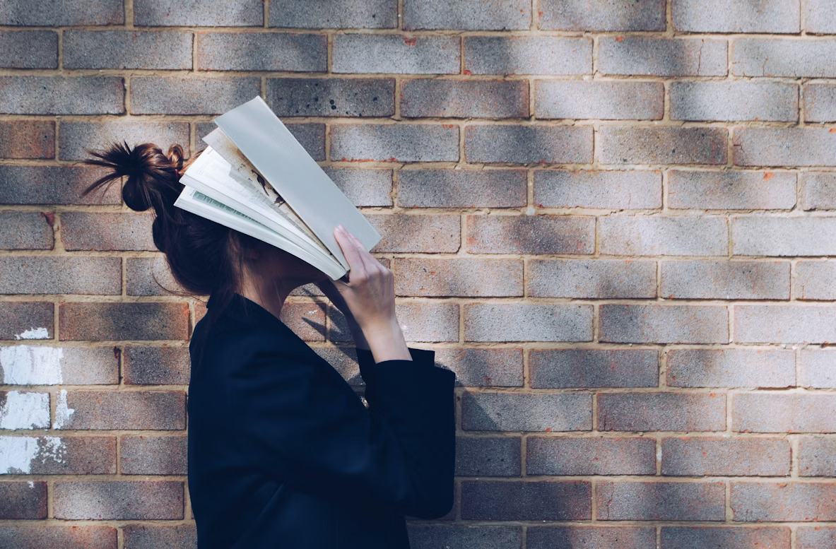 Girl covering her face with a book