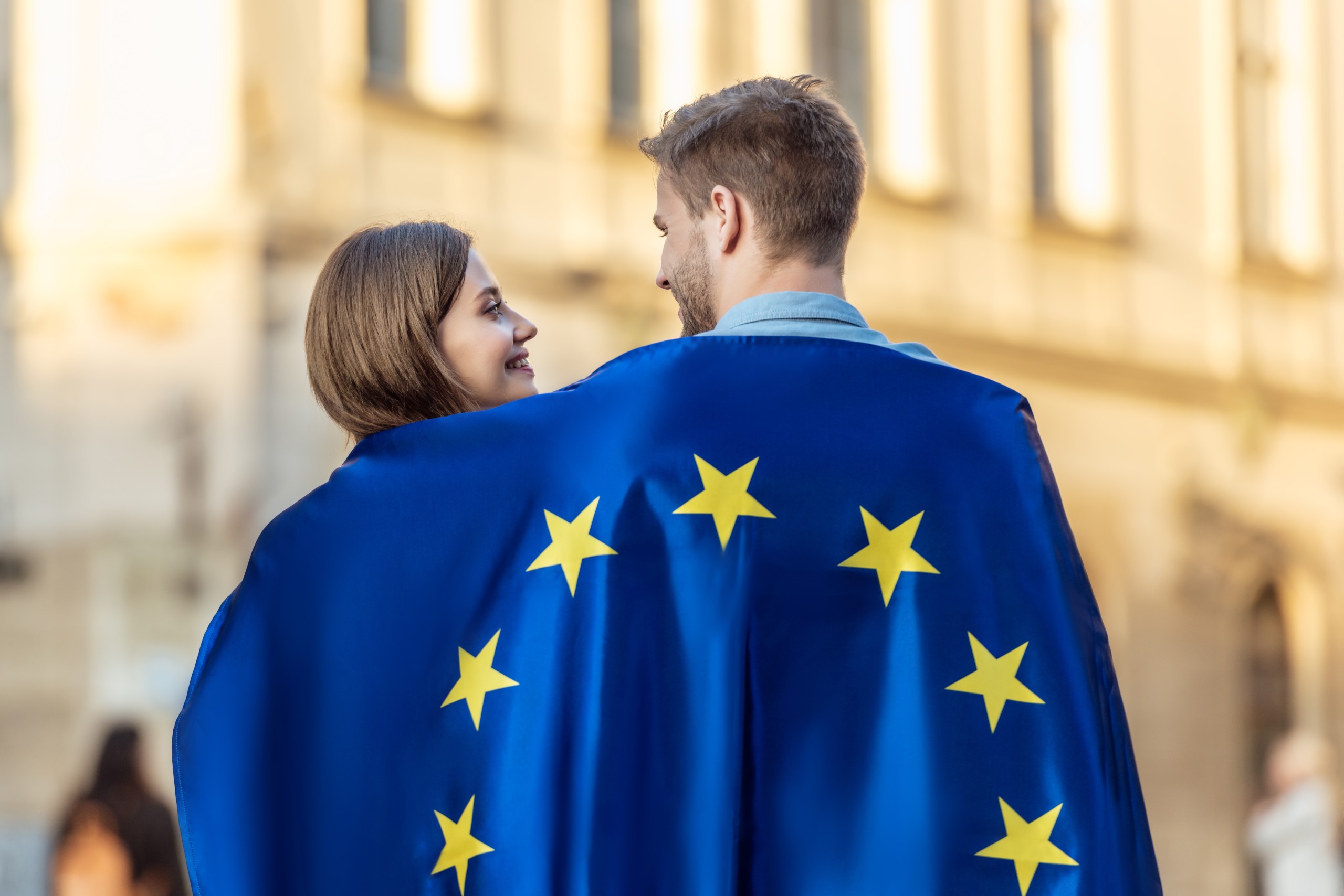Young couple of tourists wrapped in the flag of Europe