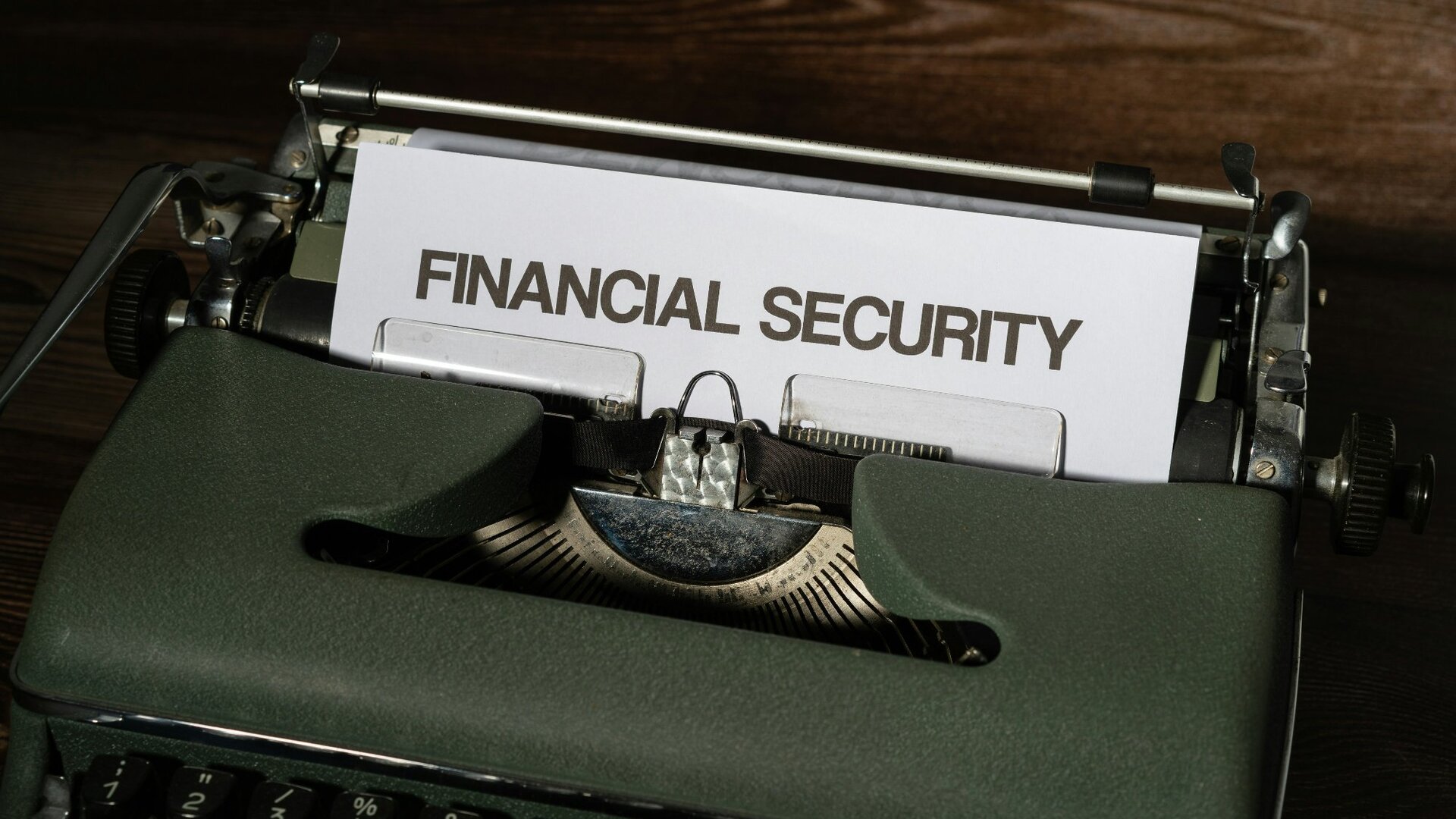 Close-up of a dark green vintage typewriter with a sheet of paper reading 'FINANCIAL SECURITY' in bold capitals.