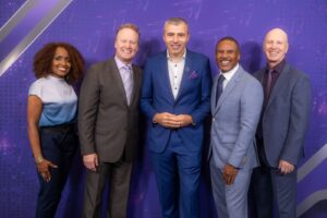 Florin Lungu with event speakers Florin Lungu stands smiling with four other professionals in business attire at an event, posing in front of a purple branded backdrop