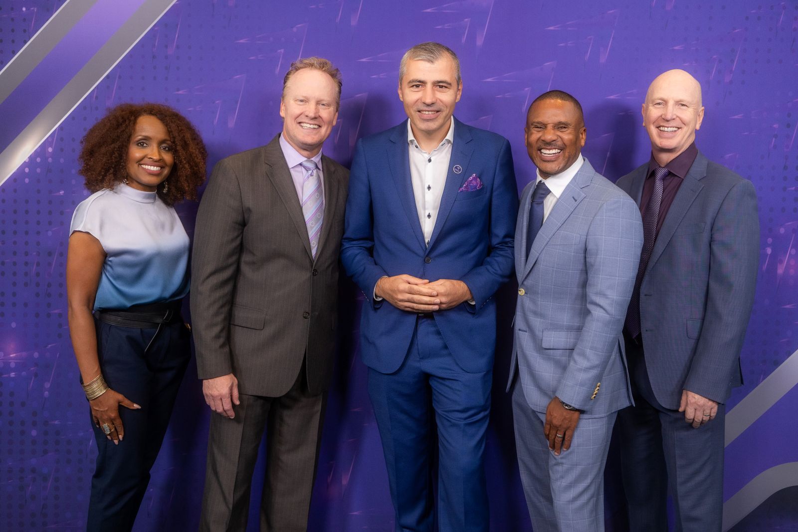 Florin Lungu stands smiling with four other professionals in business attire at an event, posing in front of a purple branded backdrop