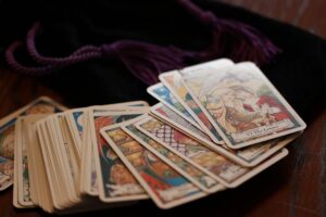 Tarot cards fanned on wood Close-up of tarot cards fanned on a dark wooden table, including The Lovers, resting on a black velvet pouch with purple drawstring tassels