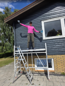 Standing atop a ladder and painting 